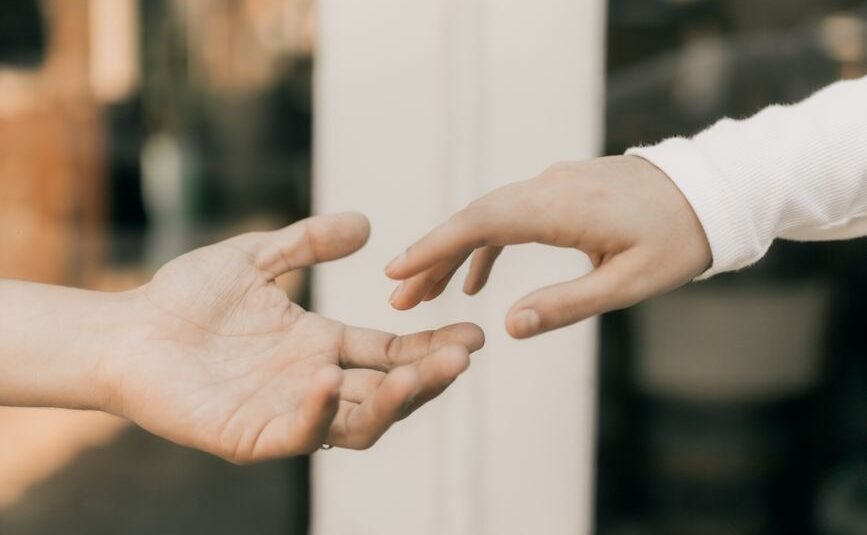 hands reaching towards each other in soft light
