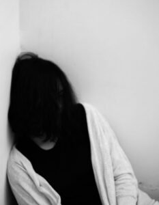 lady with face hidden leaning on wall in corner